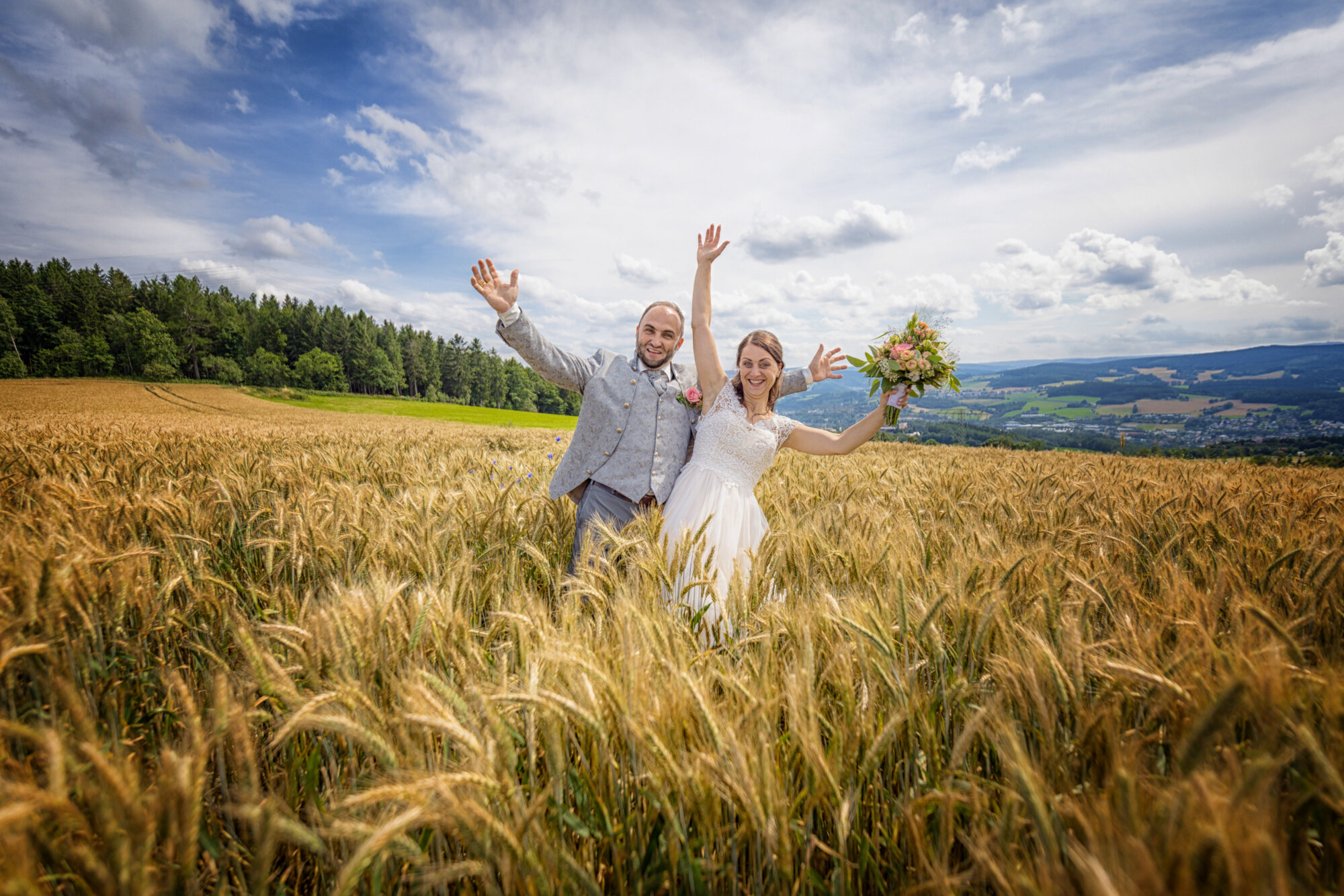 Brautpaar jubelt im goldenen Kornfeld unter blauem Himmel – Hochzeitsfotograf Marko Lorenz